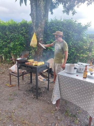 a man is standing next to a grill with a grill at Finca Villa Rosita Guamal - Meta in Guamal