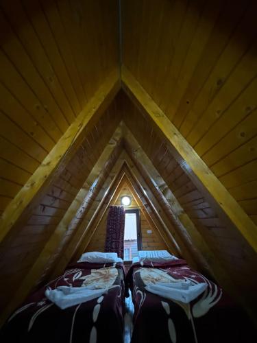 two beds in a wooden attic with a window at Thethi Paradise Hotel & Restaurant in Theth