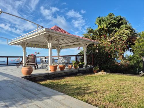 a gazebo with potted plants on a deck at Villa vue panoramique sur La Réserve Cousteau in Bouillante