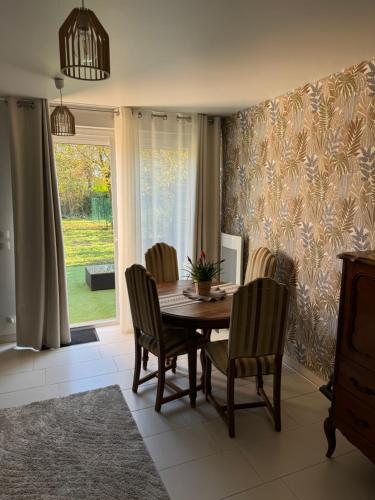 a dining room with a table and chairs and a window at La maison de Charlotte in Auvers-sur-Oise
