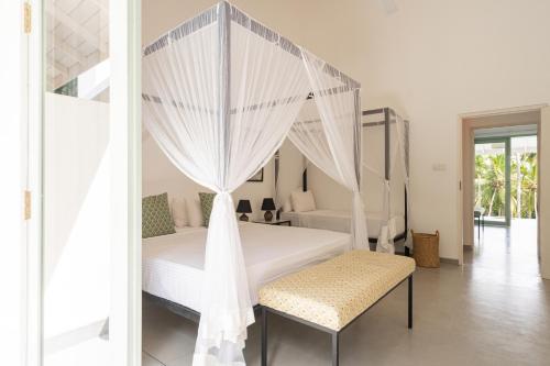 a bedroom with a white bed with a canopy at Villa Vanna in Unawatuna