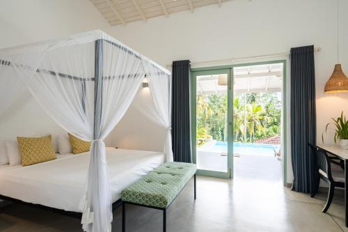 a bedroom with a bed and a desk and a window at Villa Vanna in Unawatuna