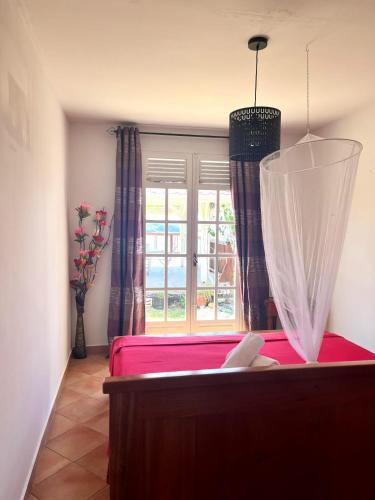 a bedroom with a pink bed and a window at Villa vue panoramique sur La Réserve Cousteau in Bouillante