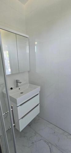 a white bathroom with a sink and a mirror at Royal Apartments in Povljana