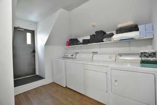 Saint-PascalにあるChambre 303 de l'hôtel Victoria confortable et moderneの白いランドリールーム(洗濯機、棚付)