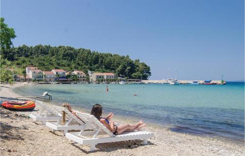 two women sitting on lounge chairs on a beach at Holiday Home Zuljana 21 in Žuljana