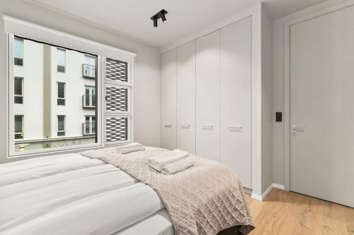 a white bedroom with a bed and a window at City Lux 2BR & 2BA with Free Parking City Center in Reykjavík