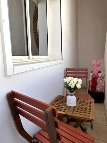 a table and bench with a vase of flowers on it at Modern appartement in Agadir in Agadir