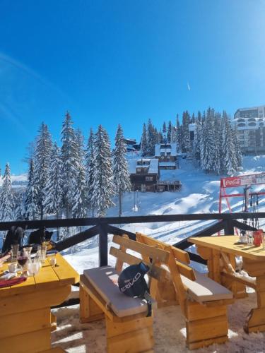 a deck with tables and chairs and snow covered trees at Jahorina Apartman Dvosjed B 10 in Jahorina