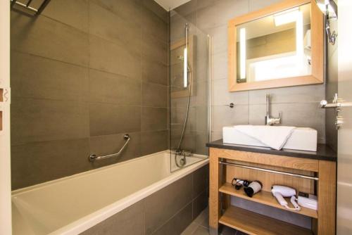 une salle de bain avec un lavabo, une baignoire et un miroir dans l'établissement Résidence Les Monarques - MONARQUES 301 MAE-0041, à Arc 1800