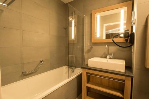 une salle de bain avec un lavabo, une baignoire et un miroir dans l'établissement Résidence Les Monarques - MONARQUES 703 MAE-0061, à Arc 1800