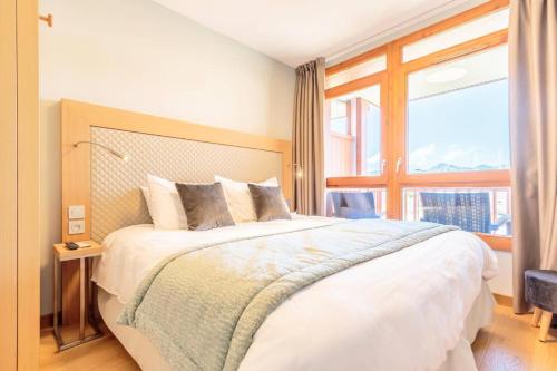 une chambre avec un grand lit avec une grande fenêtre dans l'établissement Résidence Les Monarques - MONARQUES 912 MAE-0141, à Arc 1800