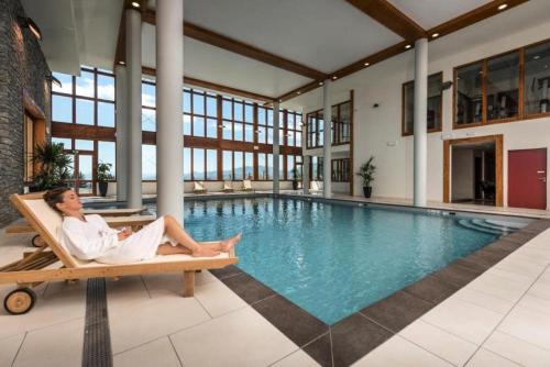 un homme assis dans une chaise à côté d'une piscine dans l'établissement Résidence Les Monarques - MONARQUES 912 MAE-0141, à Arc 1800