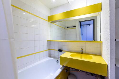 La salle de bains est pourvue d'un lavabo jaune et d'une baignoire. dans l'établissement Résidence Le De 4 - Appartement 2 pièces pour 5 personnes de 26m² MAE-0361, à La Plagne Tarentaise