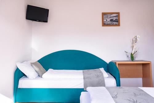 a room with two beds and a tv on the wall at Hotel Garden in Folgaria