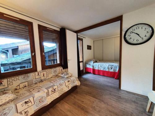 Cette chambre dispose d'une horloge murale et d'un lit. dans l'établissement Résidence Le Trompe L'oeil - TROMPE L'OEIL 28 MAE-0491, à La Plagne Tarentaise