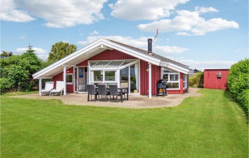a red house with chairs and tables in a yard at Amazing Home In Sæby With Sauna in Sæby
