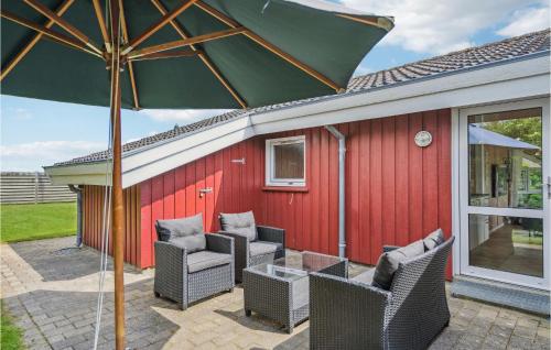 a patio with chairs and an umbrella next to a red building at Amazing Home In Sæby With Sauna in Sæby