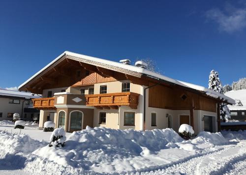 una casa ricoperta di neve con un mucchio di neve di Familie Meilinger - Werfenweng Ferienappartement a Werfenweng