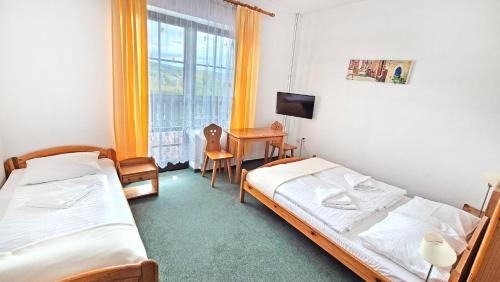 a bedroom with two beds and a desk and a window at VILLA MEDICA - Ośrodek wypoczynkowy z basenem oraz pełnym wyżywieniem in Rabka