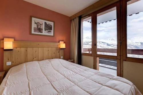 une chambre avec un grand lit et une grande fenêtre dans l'établissement Résidence La Marelle - MARELLE 517 MAE-0721, à La Plagne Tarentaise