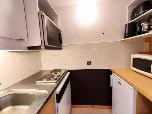 une petite cuisine avec un évier et un micro-ondes dans l'établissement Résidence Le Trompe L'oeil - TROMPE L’OEIL 13 MAE-0741, à La Plagne Tarentaise