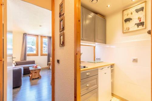 une cuisine et un salon avec un canapé dans l'établissement Résidence Le Trompe L'oeil - TROMPE L'OEIL 25 MAE-0771, à La Plagne Tarentaise
