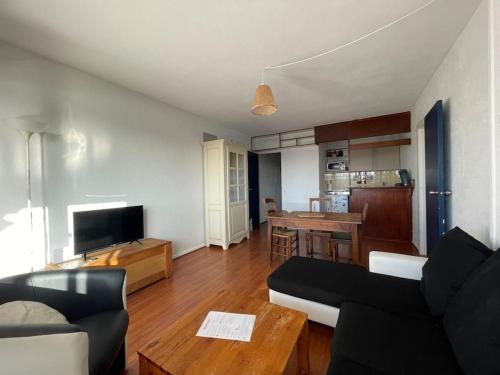 un salon avec un canapé et une table dans l'établissement Appartement avec balcon vue sur le port & piscine, à Capbreton