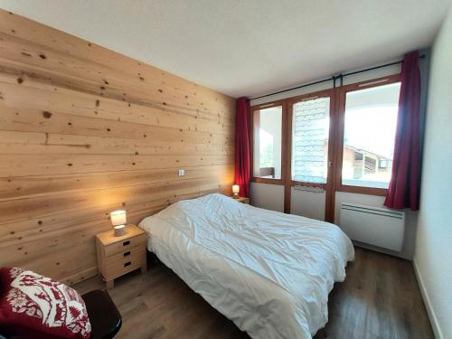 - une chambre dotée d'un mur en bois avec un lit et deux lampes dans l'établissement Résidence Le De 3 - Appartement 3 pièces pour 6 personnes de 45m² MAE-0891, à La Plagne Tarentaise