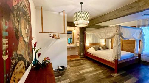 a bedroom with a canopy bed and a chandelier at Habitation Caféière Samana Beauséjour - GUESTHOUSE in Pointe-Noire