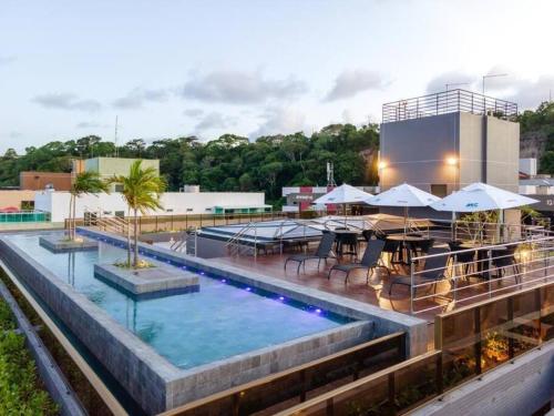 a pool with tables and umbrellas on top of a building at Unity, Cabo Branco Flat 324 in João Pessoa