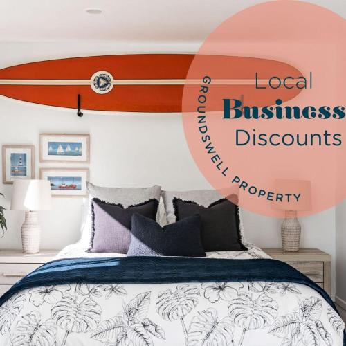 a surfboard hanging on a wall above a bed at Kowhai Cottage & Studio in Raglan