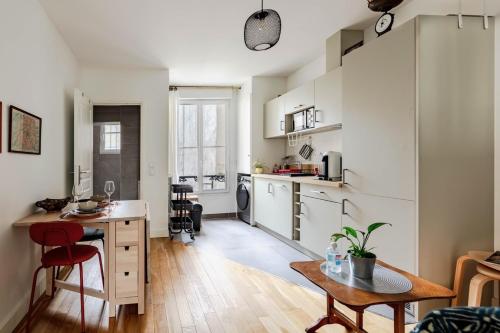 une cuisine avec des armoires blanches et une table dans une pièce dans l'établissement Charmant studio cosy au cœur du Village Ramey Montmartre Métro 12, à Paris