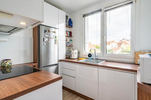 une cuisine avec des placards blancs et une grande fenêtre dans l'établissement 20mins à Paris, Rueil-Malmaison à côté de la gare, à Rueil-Malmaison