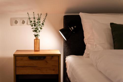 a vase on a night stand next to a bed at dreamcation Altstadthotel Regensburg, Mikro Apartments mit Küche in Regensburg
