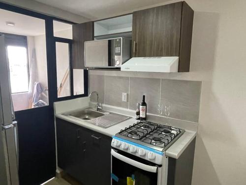 a small kitchen with a stove and a sink at Departamento cerca Palacio Deportes, Estadio GNP, Aeropuerto AICM, Autódromo in Mexico City