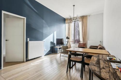 un salon avec une table et un mur bleu dans l'établissement Appartement Le Rostand, à Montrouge
