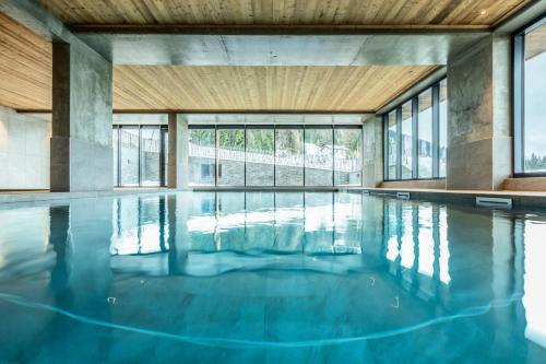 - une piscine d'eau bleue dans un bâtiment avec fenêtres dans l'établissement Résidence Le Ridge - RIDGE 301 MAE-5081, à Arc 1600