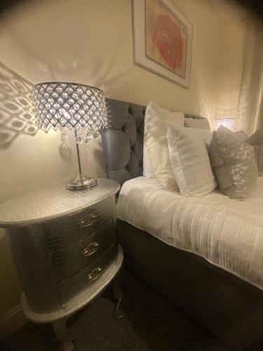 a bedroom with a bed and a table with a lamp at Stylish & Cosy Apartment in Bristol