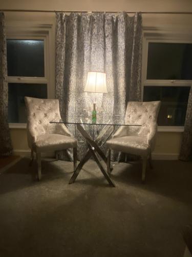 a glass table with two chairs and a lamp in a room at Stylish & Cosy Apartment in Bristol