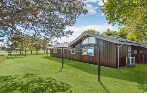 a small wooden house on a lawn with trees at Cozy Home In Hjørring With Sauna in Lønstrup