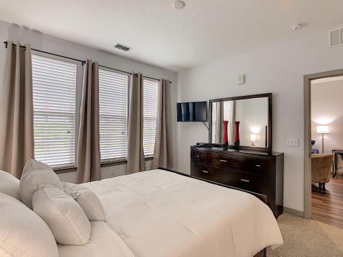 a bedroom with a large white bed and a mirror at Convenient and Close to All in Kissimmee