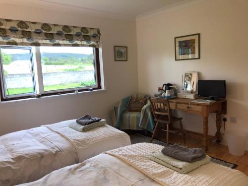 a bedroom with two beds and a desk with a computer at Rowantree in Kiltarlty