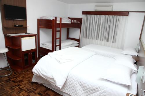 a bedroom with two bunk beds and a television at Hospedaria Gãstehaus Enzian in Treze Tílias