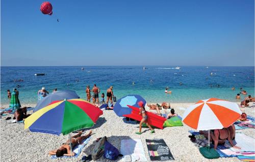 a group of people on a beach with umbrellas at Two-Bedroom Holiday Home In Tucepi in Tučepi