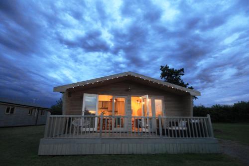 a small house with a porch with a deck at Woodpecker Lodge - Brook Meadow - sleeps 4 plus 2 - no pets in Market Harborough