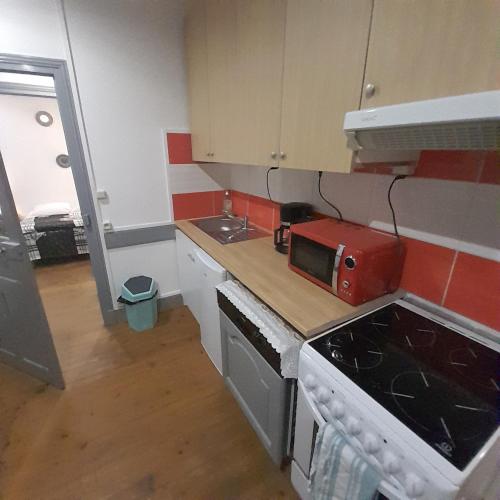 - une cuisine avec un comptoir et un four micro-ondes rouge dans l'établissement La Hall, à Thiers