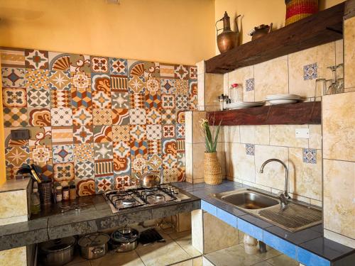 a kitchen with a sink and a tile wall at Hostal y Cabañas Renta House San Pedro in San Pedro de Atacama