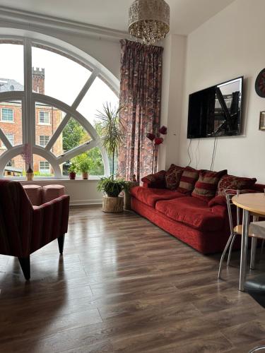 a living room with a red couch and a large window at Stunning 2 bedroom apartment in Glasgow