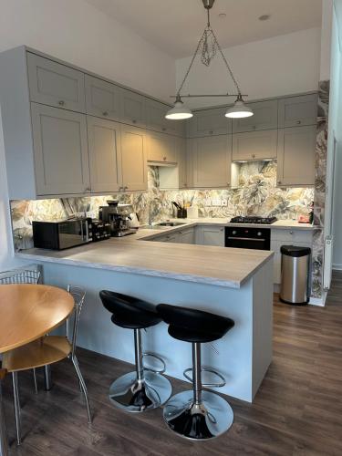 a kitchen with a counter and two bar stools at Stunning 2 bedroom apartment in Glasgow